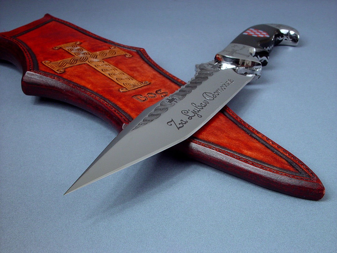 "Duhovni Ratnik" obverse side view. Knife in hand-engraved 440C high chromium stainless steel blade, hand-engraved 304 stainless steel bolsters, handle of Black Nephrite Jade gemstone inlaid with a mosaic of Red River Jasper and White Geodic Quartz. Sheath is hand-carved, hand-dyed leather shoulder